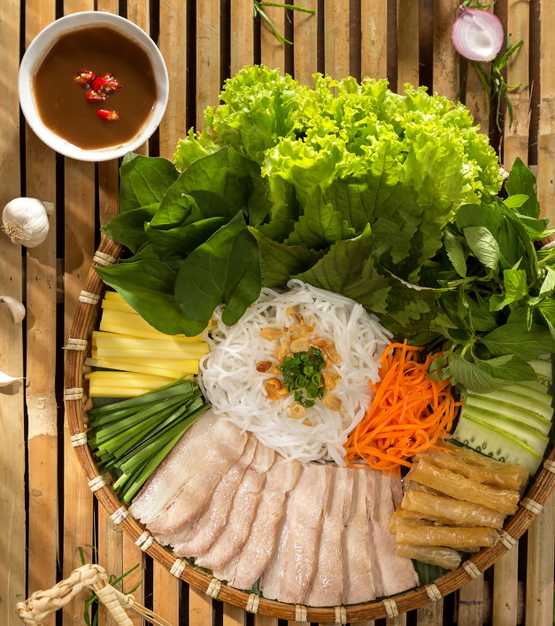 đĩa thịt luộc cuốn bánh tráng với rau và nước chấm